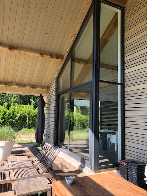 Overkapping met aluminium schuifpui en houten gevel bij een woning