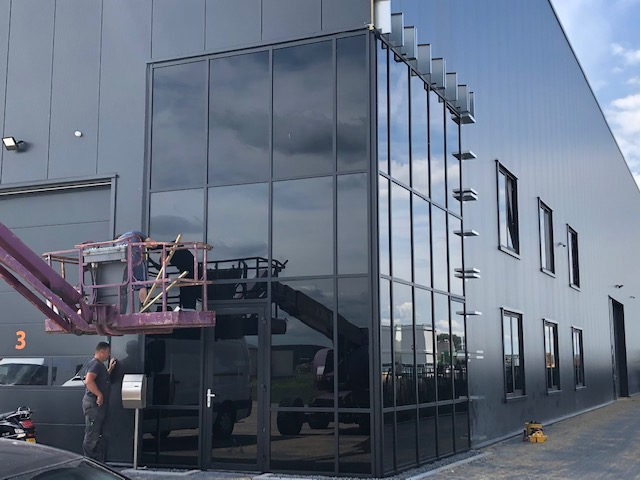 Aluminium gevel met glas en deur aan een bedrijfshal
