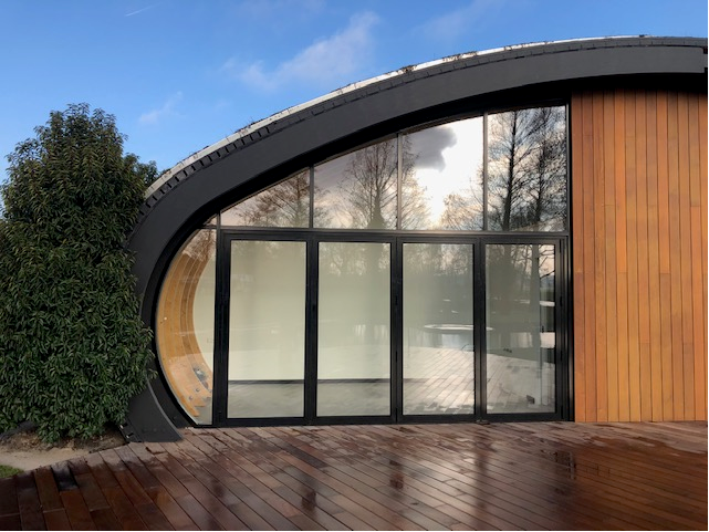 Gebogen gevel met aluminium puien en houten beschieting