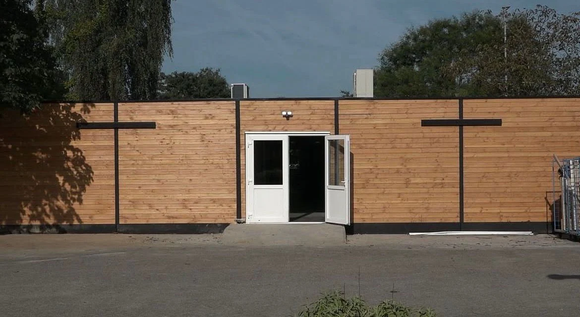 Moderne unit met houtlook-gevel en openstaande deuren op een projectlocatie